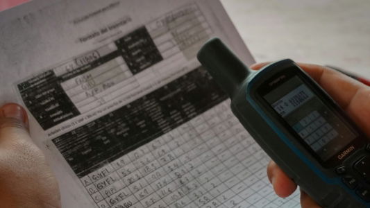 a person holding a cell phone over a piece of paper
